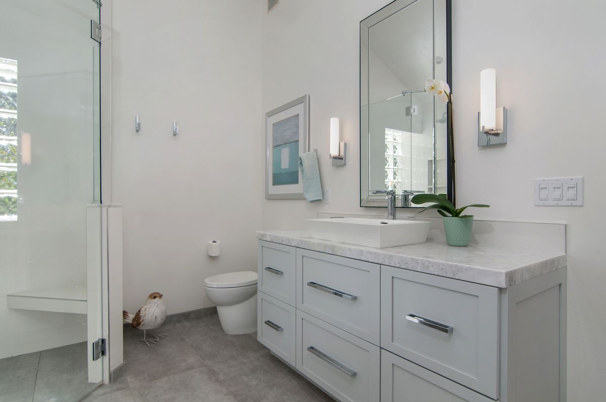 A bathroom with a toilet , sink , mirror and shower.