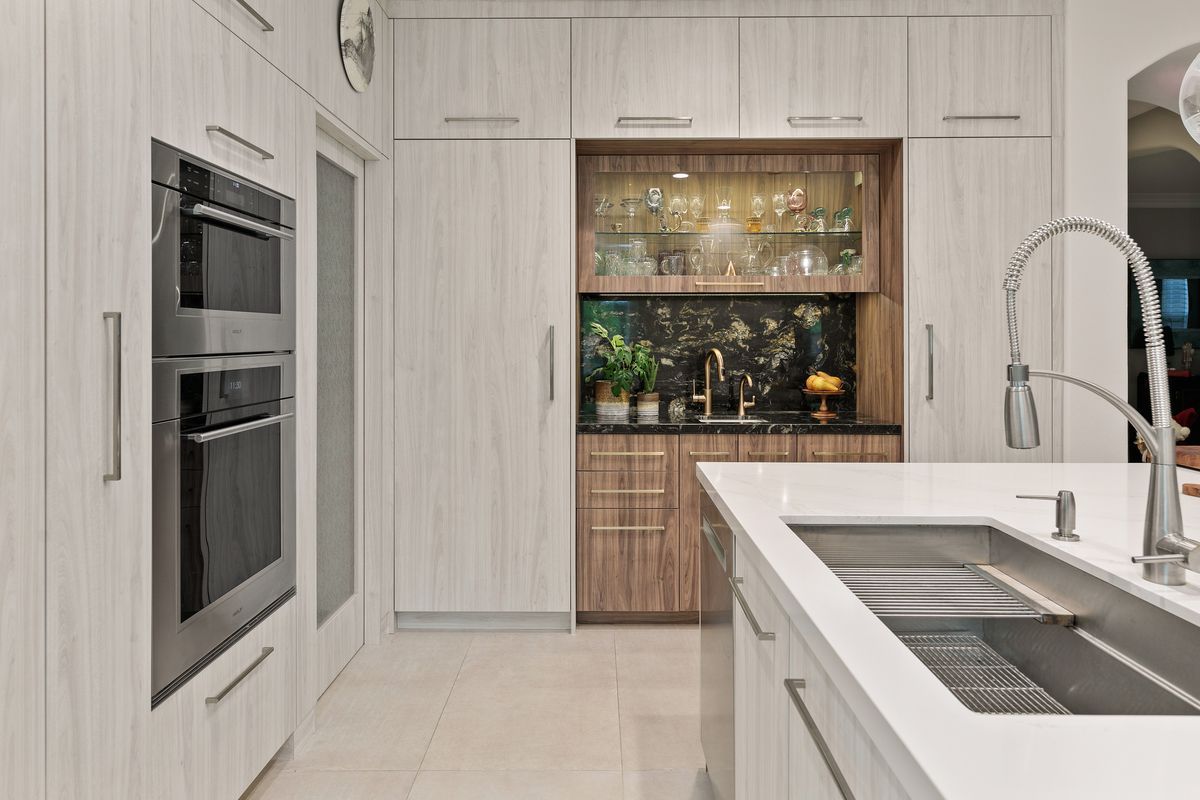 A kitchen with white cabinets , stainless steel appliances , a sink and an oven.