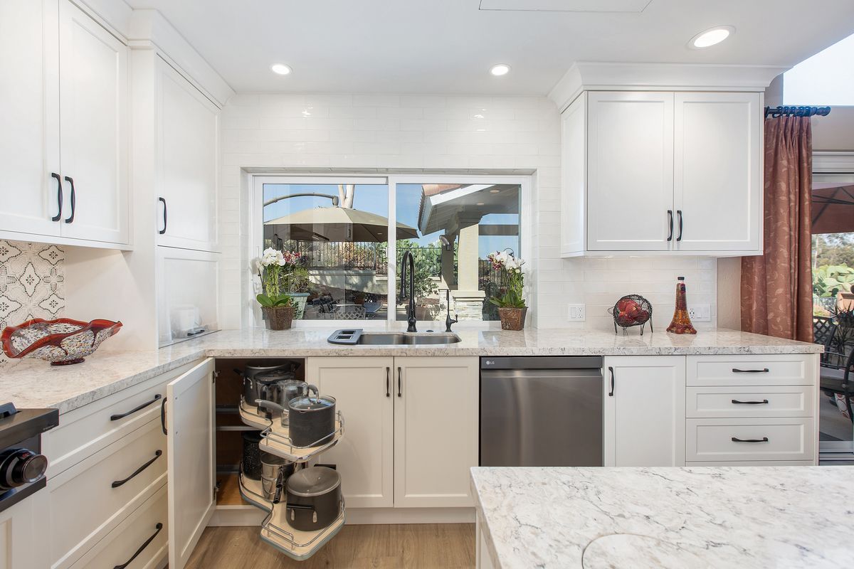 A kitchen with white cabinets , granite counter tops , stainless steel appliances and a sliding glass door.