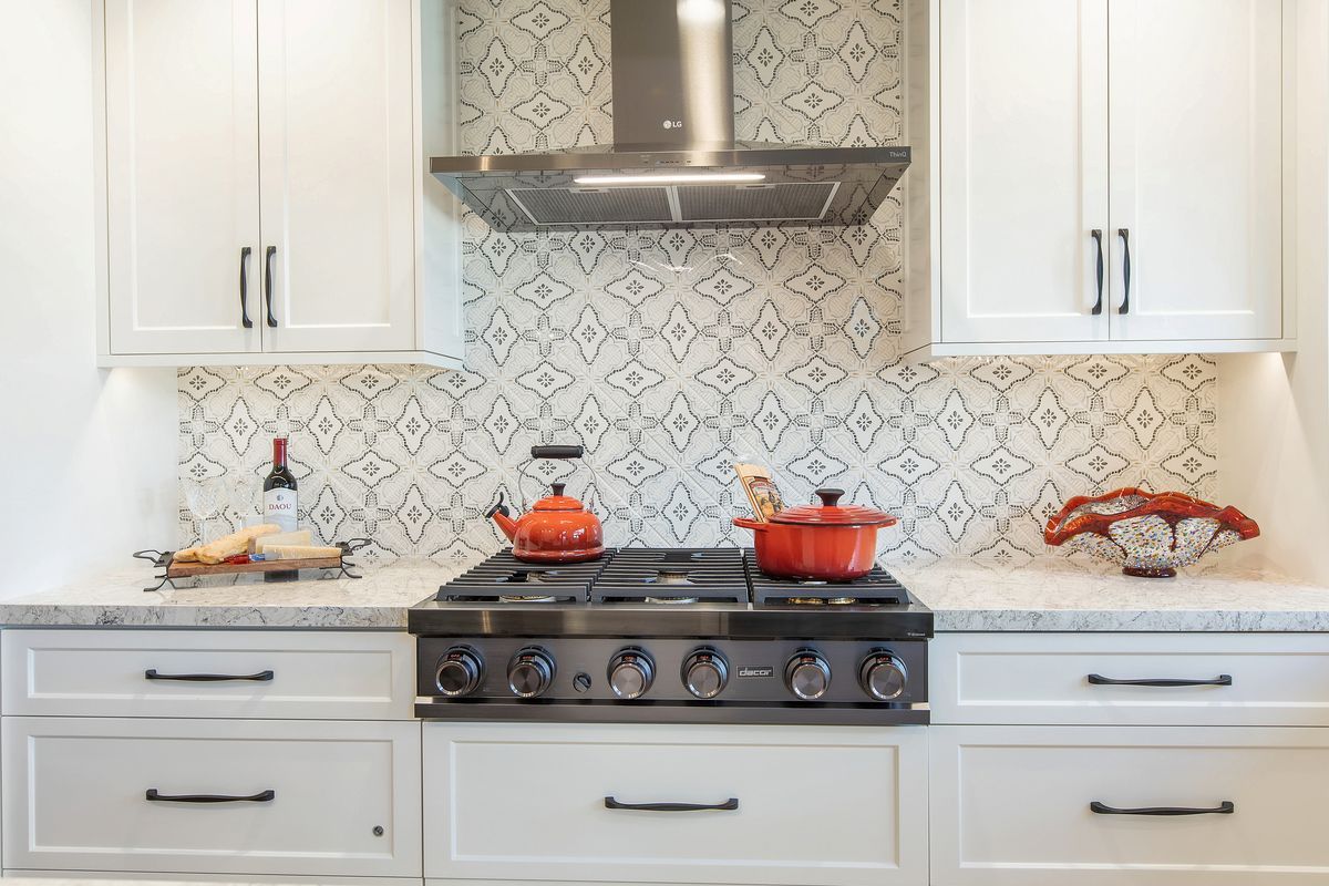 A kitchen with white cabinets and a stove top oven