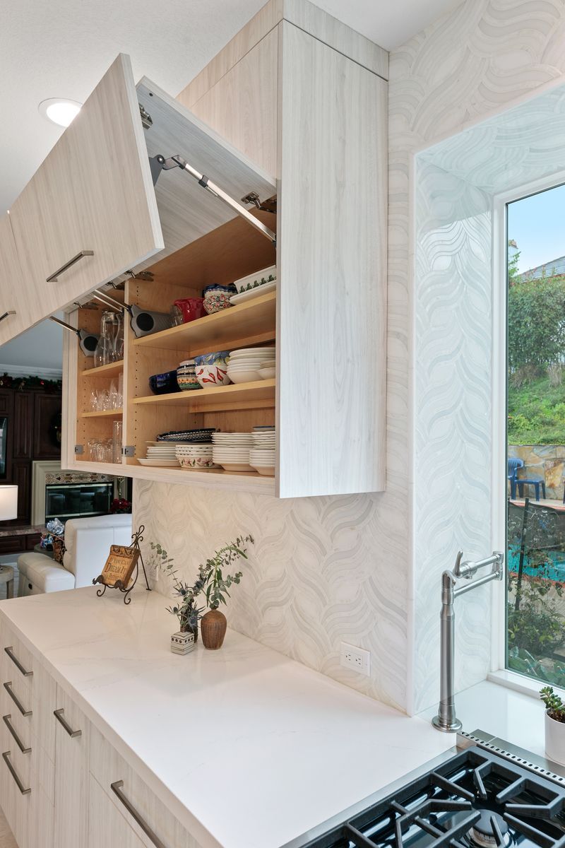 A kitchen with a stove and a window with a cabinet open.