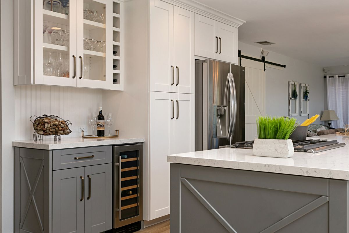 A kitchen with gray cabinets , white cabinets , a refrigerator and a wine cooler.