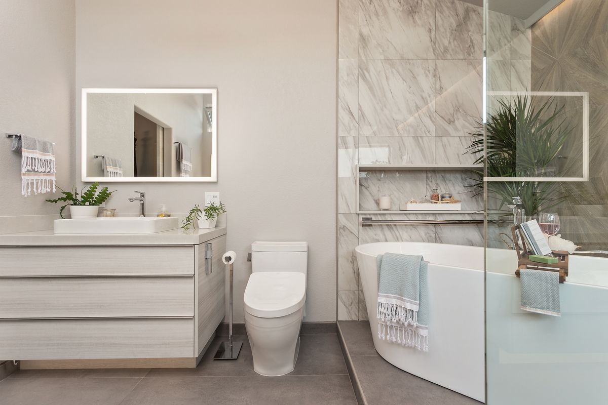 A bathroom with a toilet , sink , bathtub and mirror.