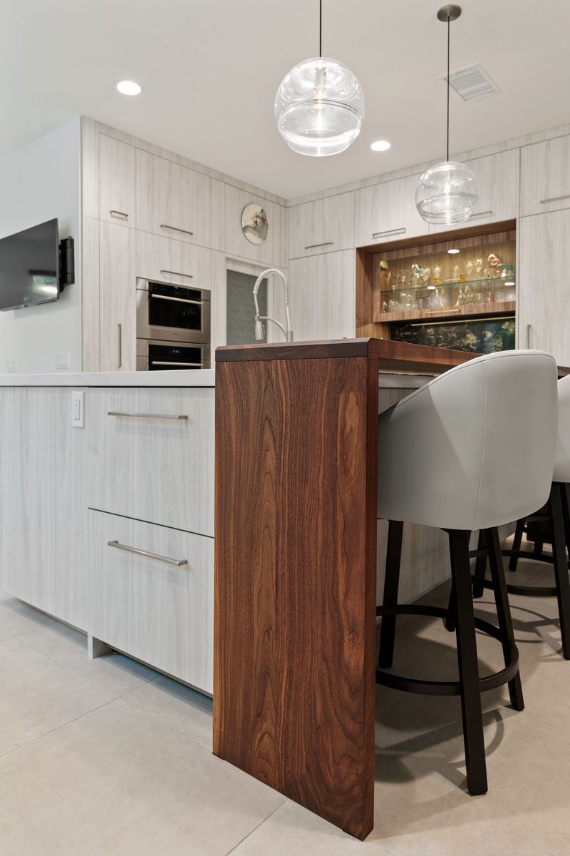 A kitchen with white cabinets , a wooden island , stools and a sink.