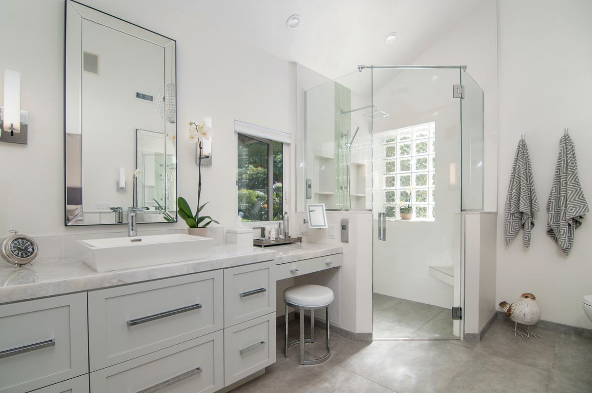 A bathroom with two sinks , a mirror and a walk in shower.