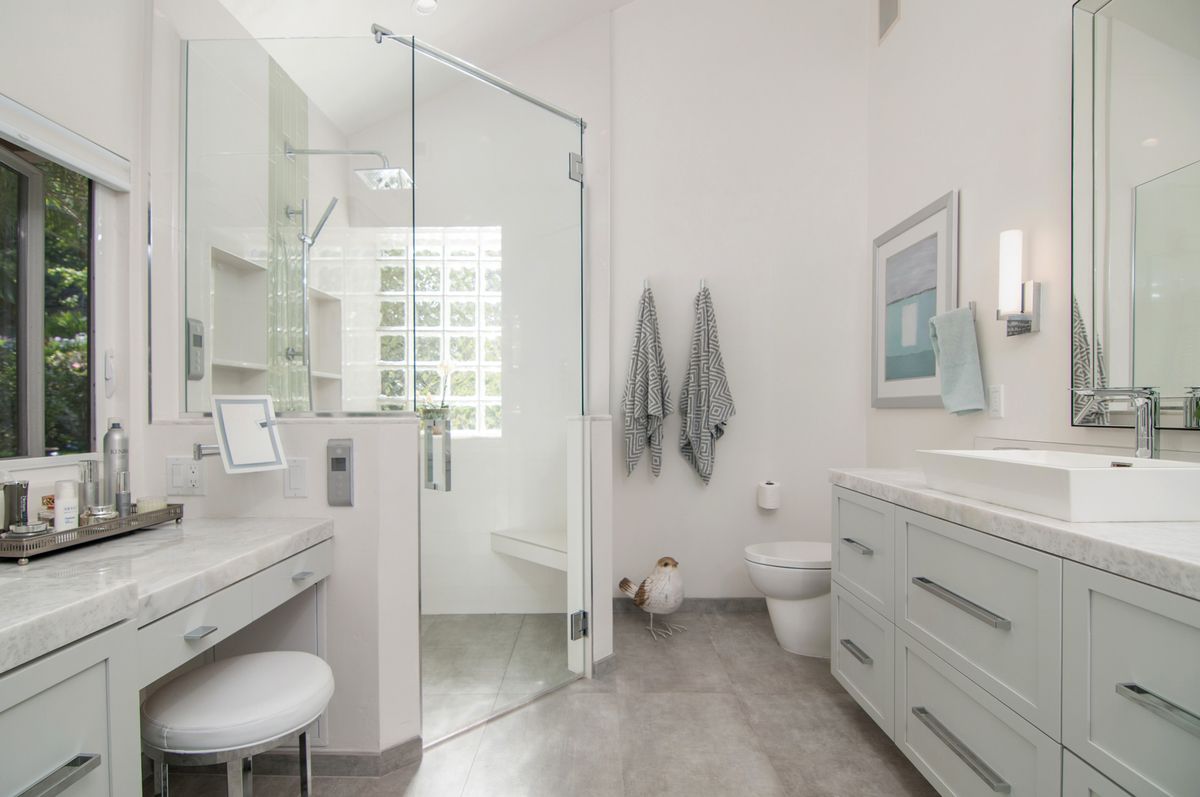 A bathroom with two sinks , a toilet , and a walk in shower.