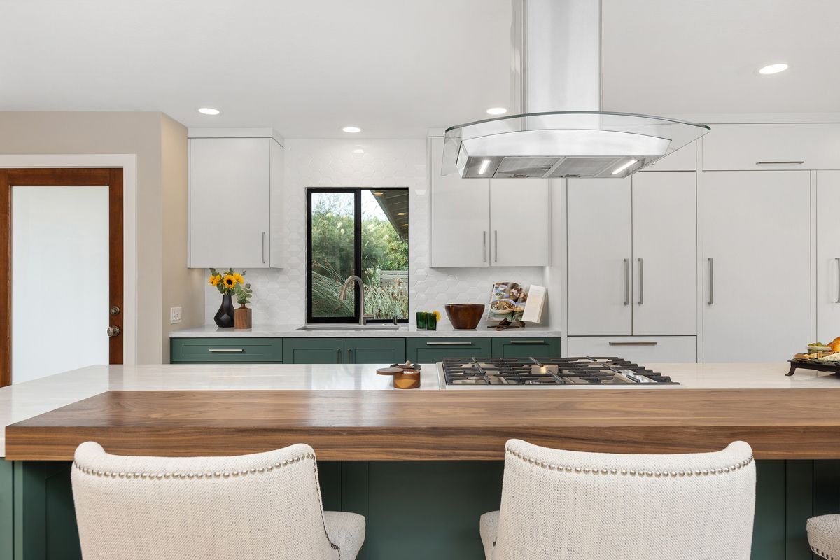 A kitchen sink with two faucets and a plant on the counter.
