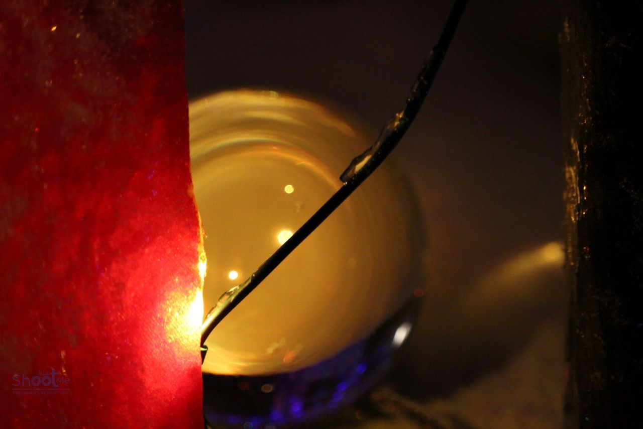 A glowing red object stands beside a spherical, illuminated orb partially crossed by a thin, dark wire.