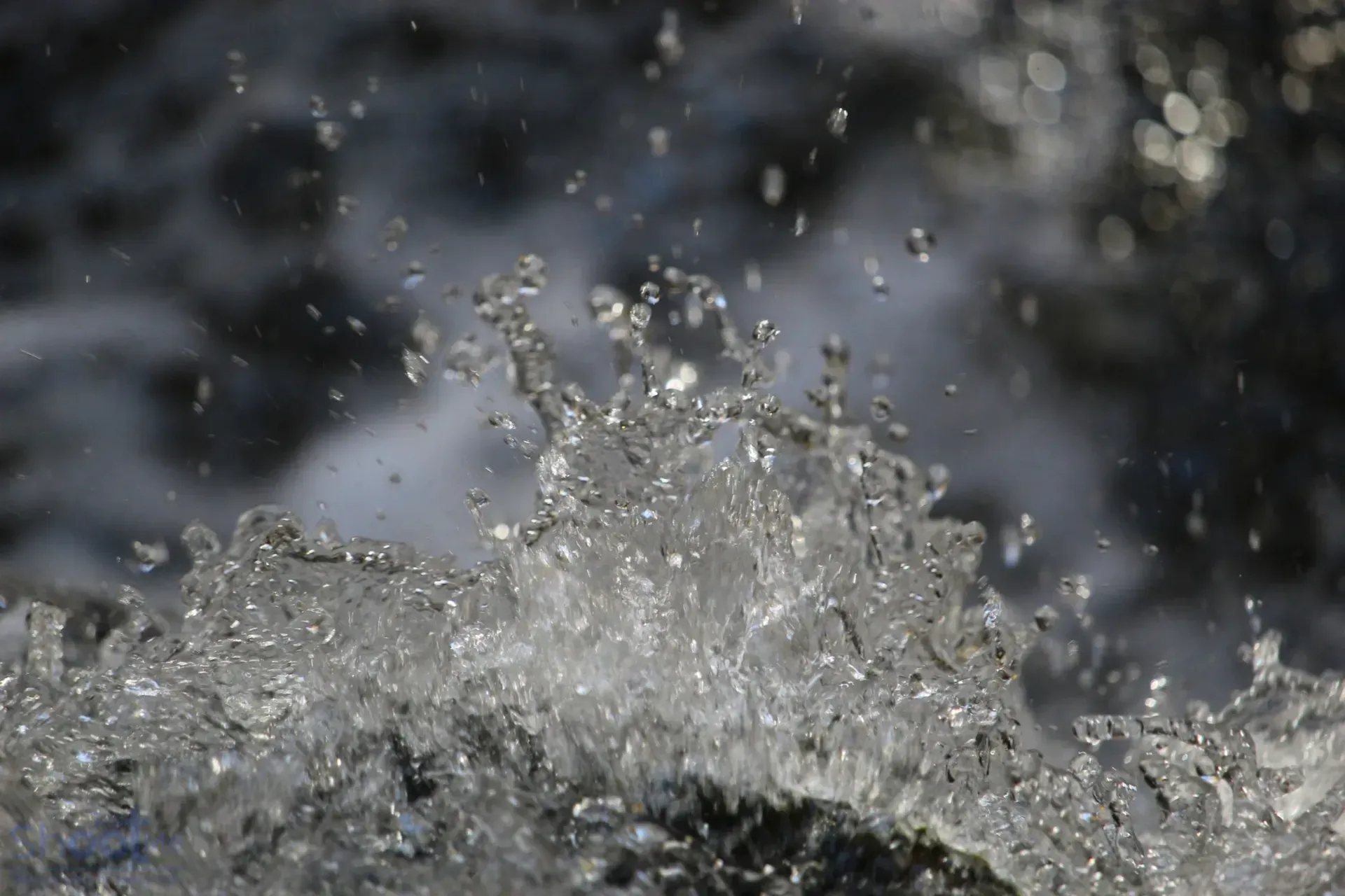Water splashing against a dark surface, creating droplets suspended in mid-air.