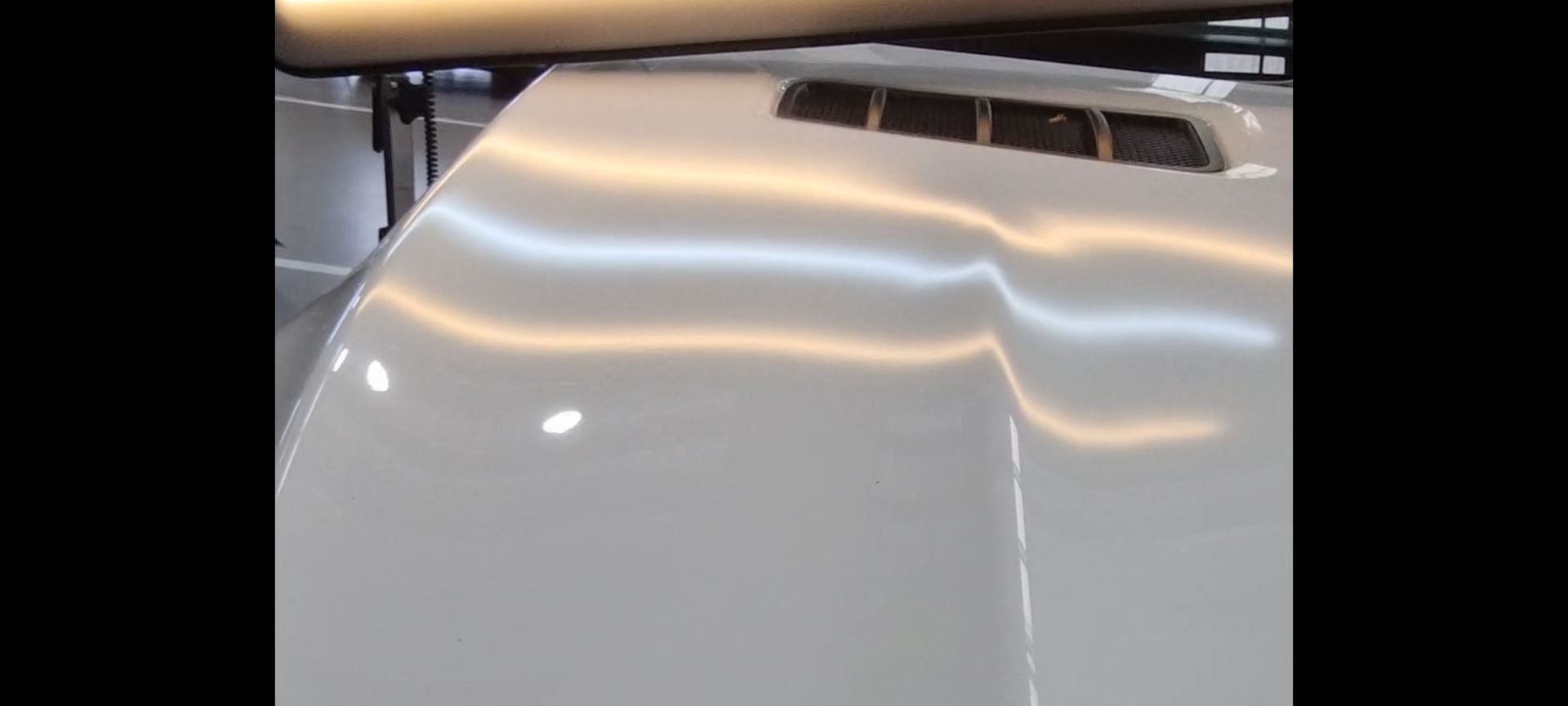 a close up of the hood of a white car with dents removed