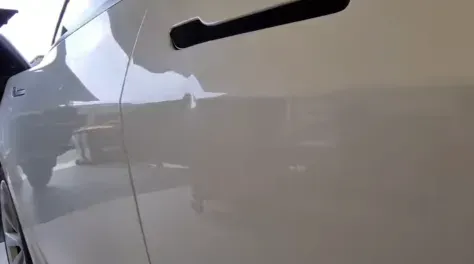 PDR technician repairing a dent on a Tesla Model 3 door panel using specialised aluminium-safe tools