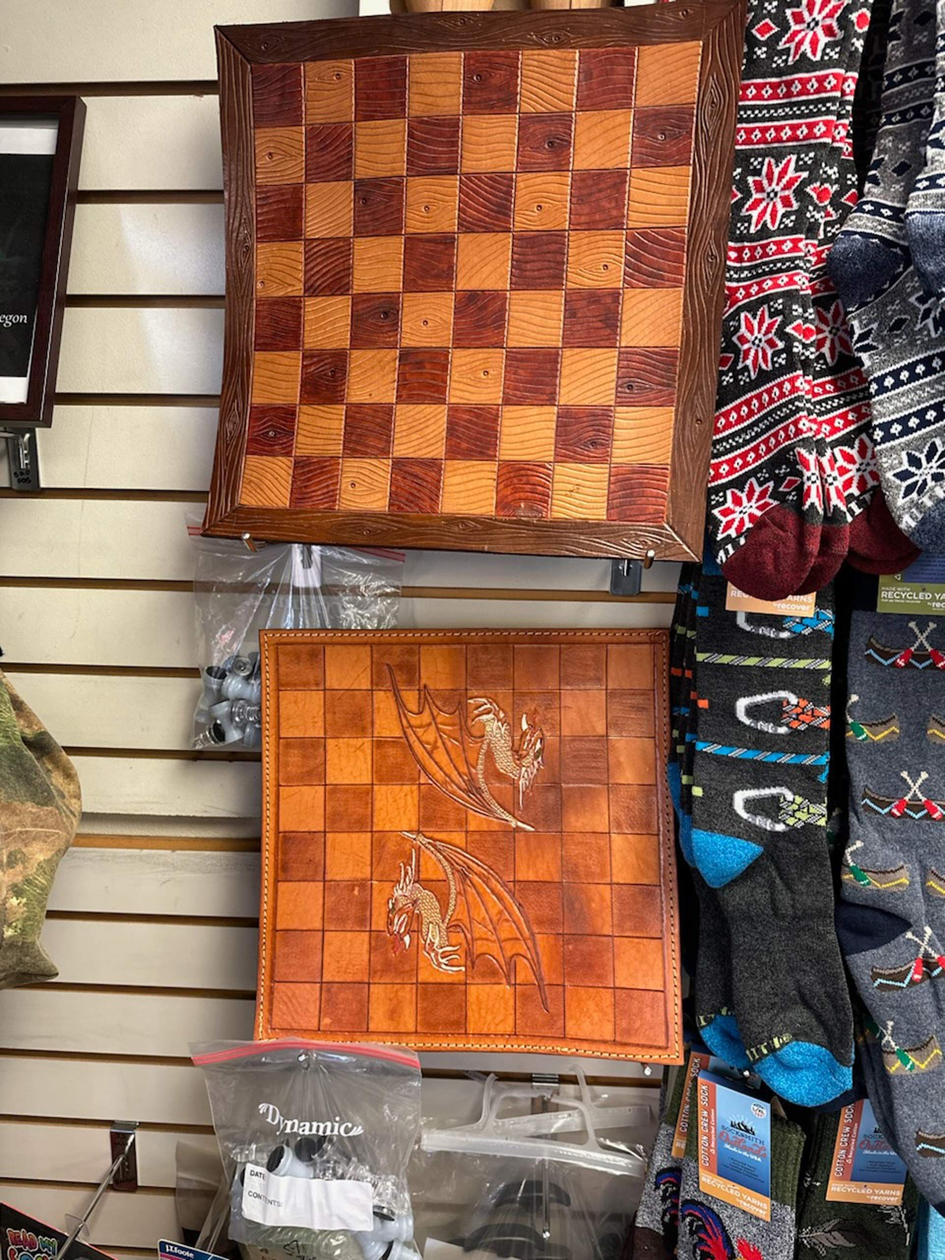A wooden chess board is hanging on a wall next to socks.