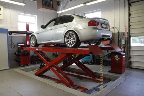 A silver car is sitting on a red lift in a garage.