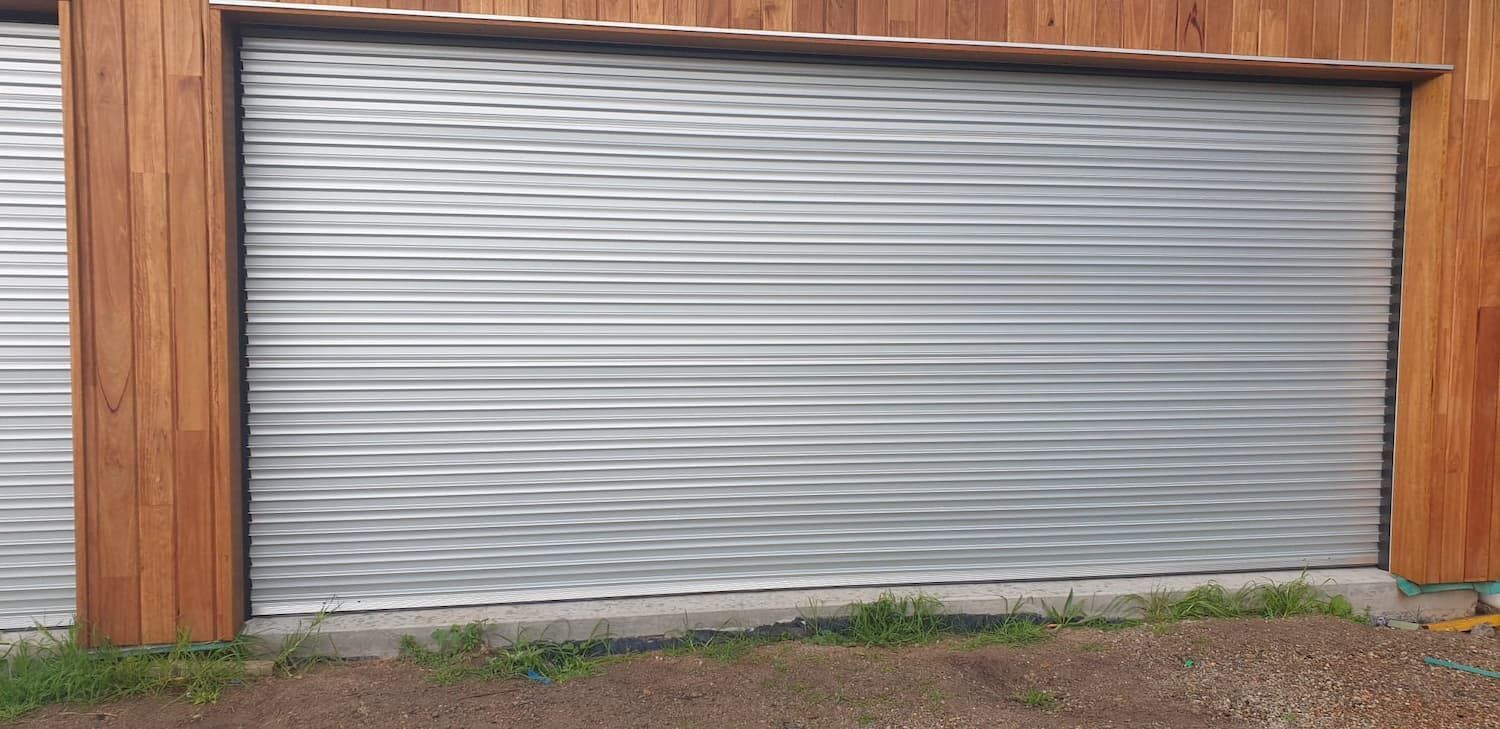 A Close up Of a Garage Door with A Wooden Wall Behind It — Illawarra Garage Doors in Albion Park Rail, NSW