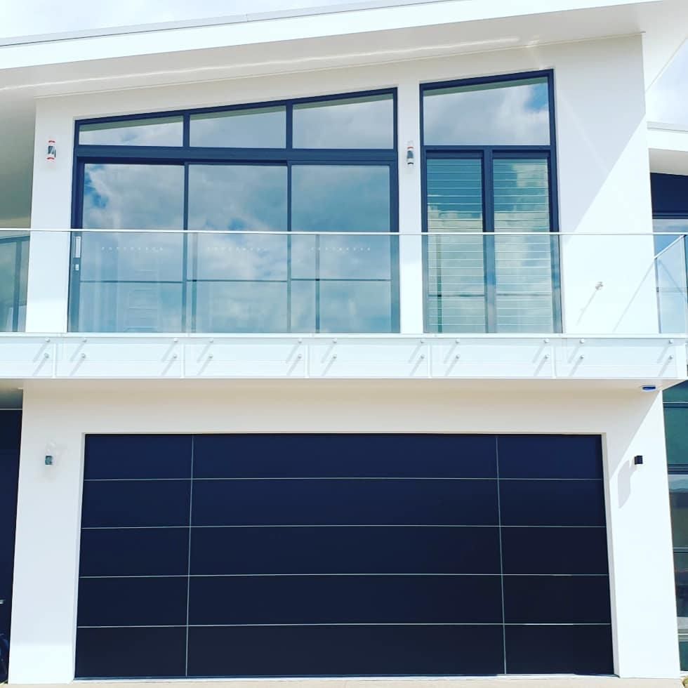 A White House with A Black Garage Door and A Balcony — Illawarra Garage Doors in Albion Park Rail, NSW