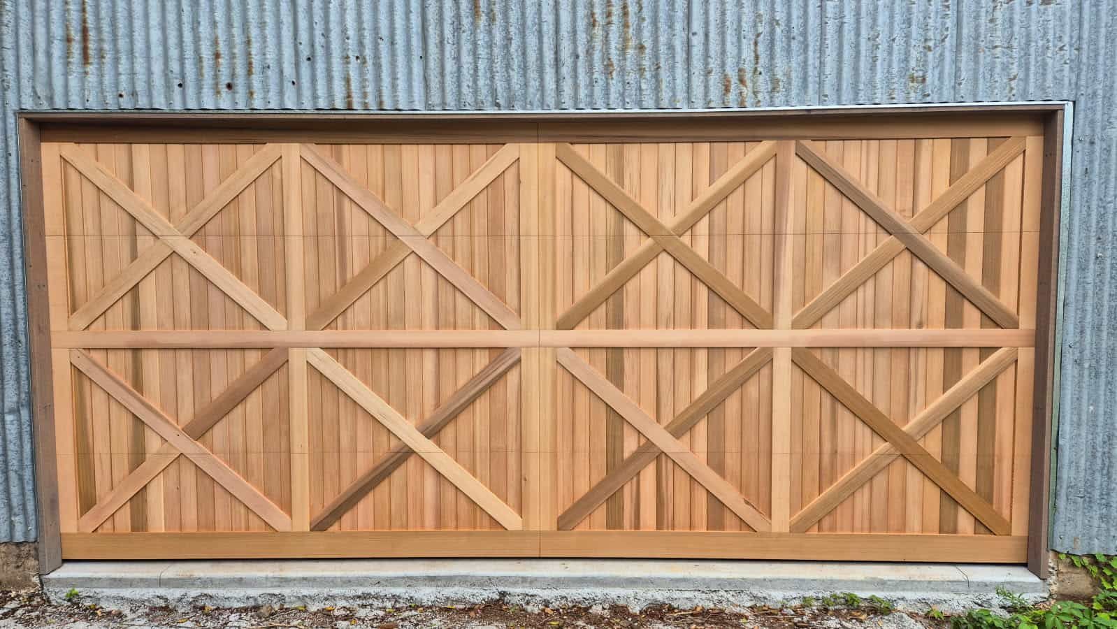A Wooden Garage Door Is Sitting in Front of A Metal Wall — Illawarra Garage Doors in Albion Park Rail, NSW