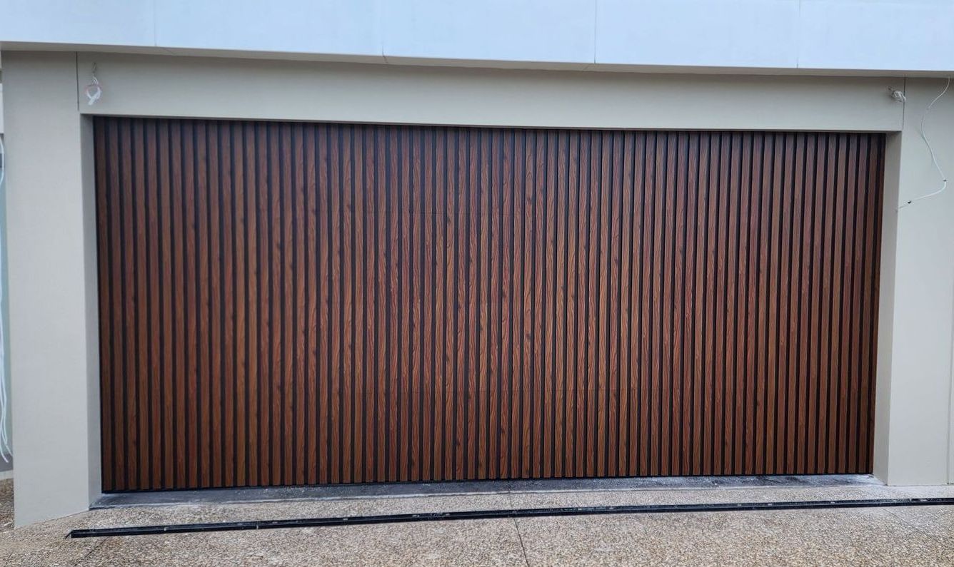 A Large Wooden Garage Door Is Sitting in Front of A Brick Building — Illawarra Garage Doors in Albion Park Rail, NSW