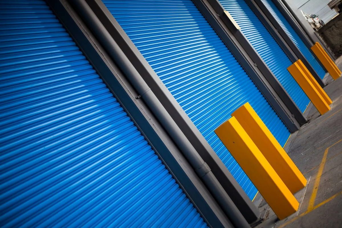 A Row of Blue Garage Doors with Yellow Pillars — Illawarra Garage Doors in Albion Park Rail, NSW