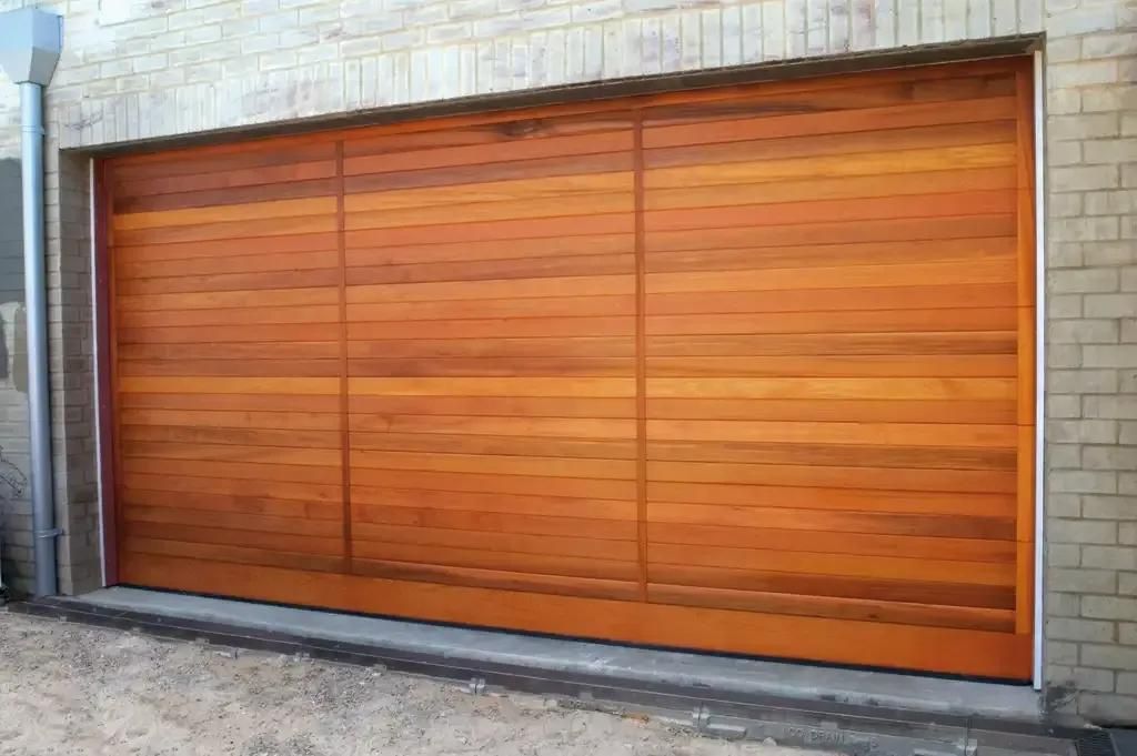A Large Wooden Garage Door Is Sitting in Front of A Brick Building — Illawarra Garage Doors in Albion Park Rail, NSW