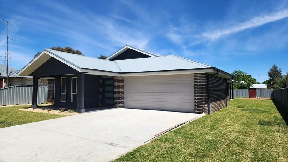 A Black and White House with A Blue Sky in The Background — Illawarra Garage Doors in Albion Park Rail, NSW