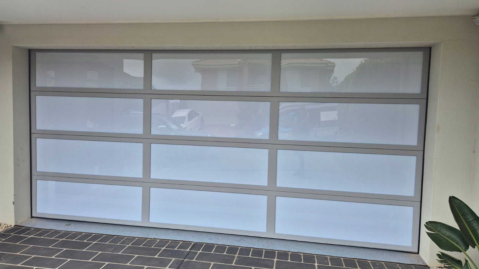 A White Garage Door with A Brick Driveway in Front of It — Illawarra Garage Doors in Albion Park Rail, NSW
