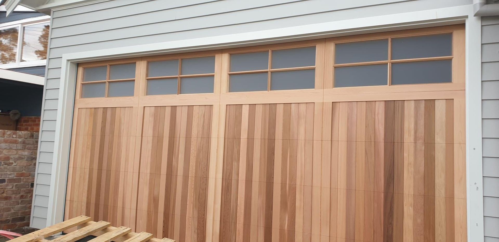 A Wooden Garage Door Is Being Installed on A House — Illawarra Garage Doors in Shellharbour, NSW