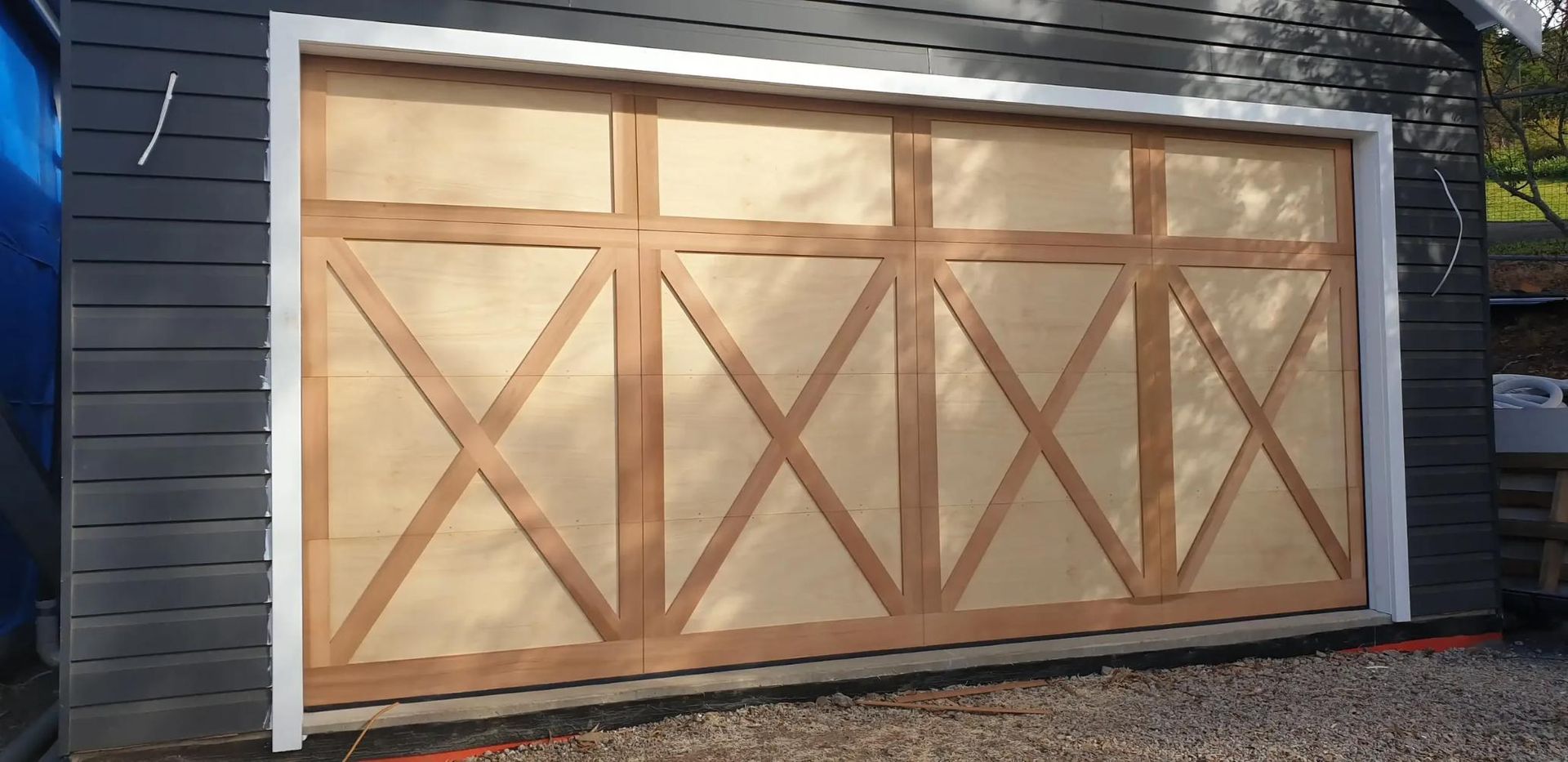 A Wooden Garage Door Is Being Built on The Side of A House — Illawarra Garage Doors in Albion Park Rail, NSW