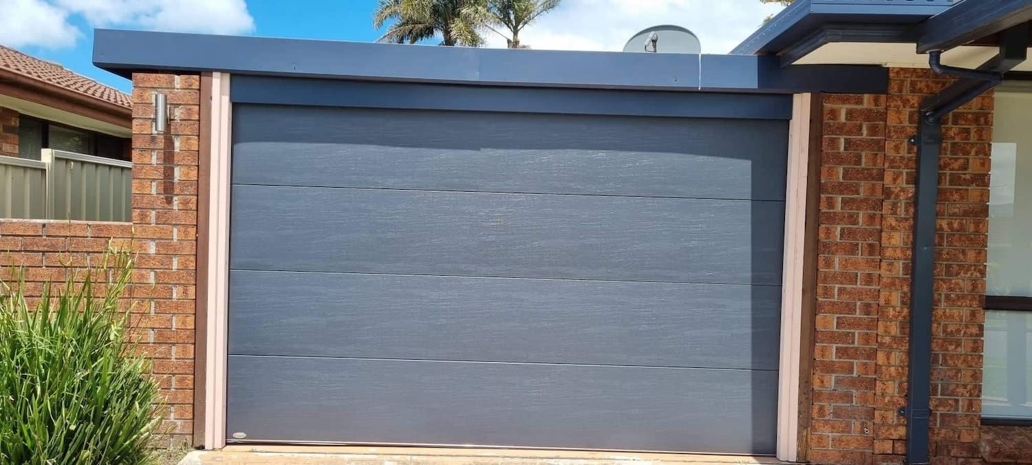 A Garage Door Is Sitting in Front of A Brick Building — Illawarra Garage Doors in Albion Park Rail, NSW