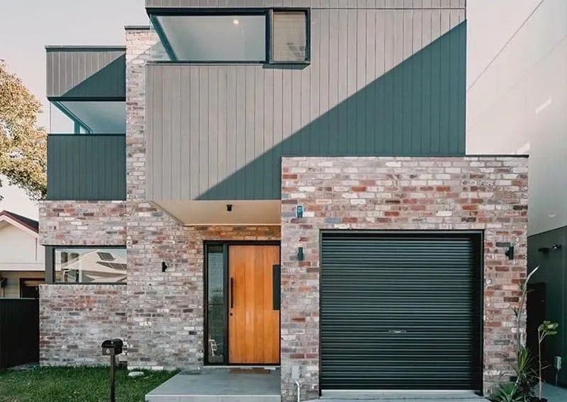 A Brick House with A Black Garage Door and A Wooden Door — Illawarra Garage Doors in Albion Park Rail, NSW