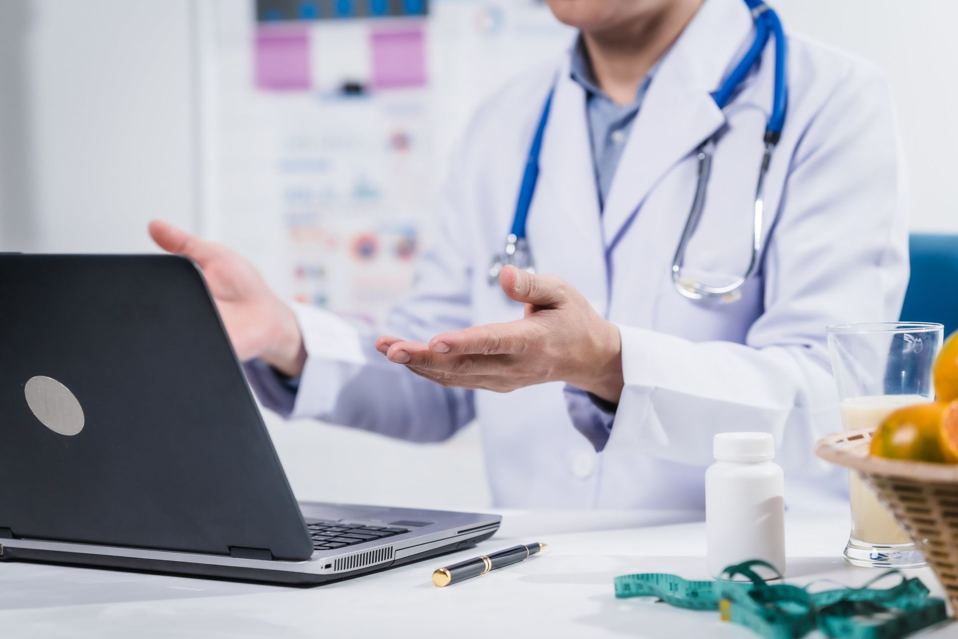 Doctor in white coat consulting beside a laptop in a clinic office