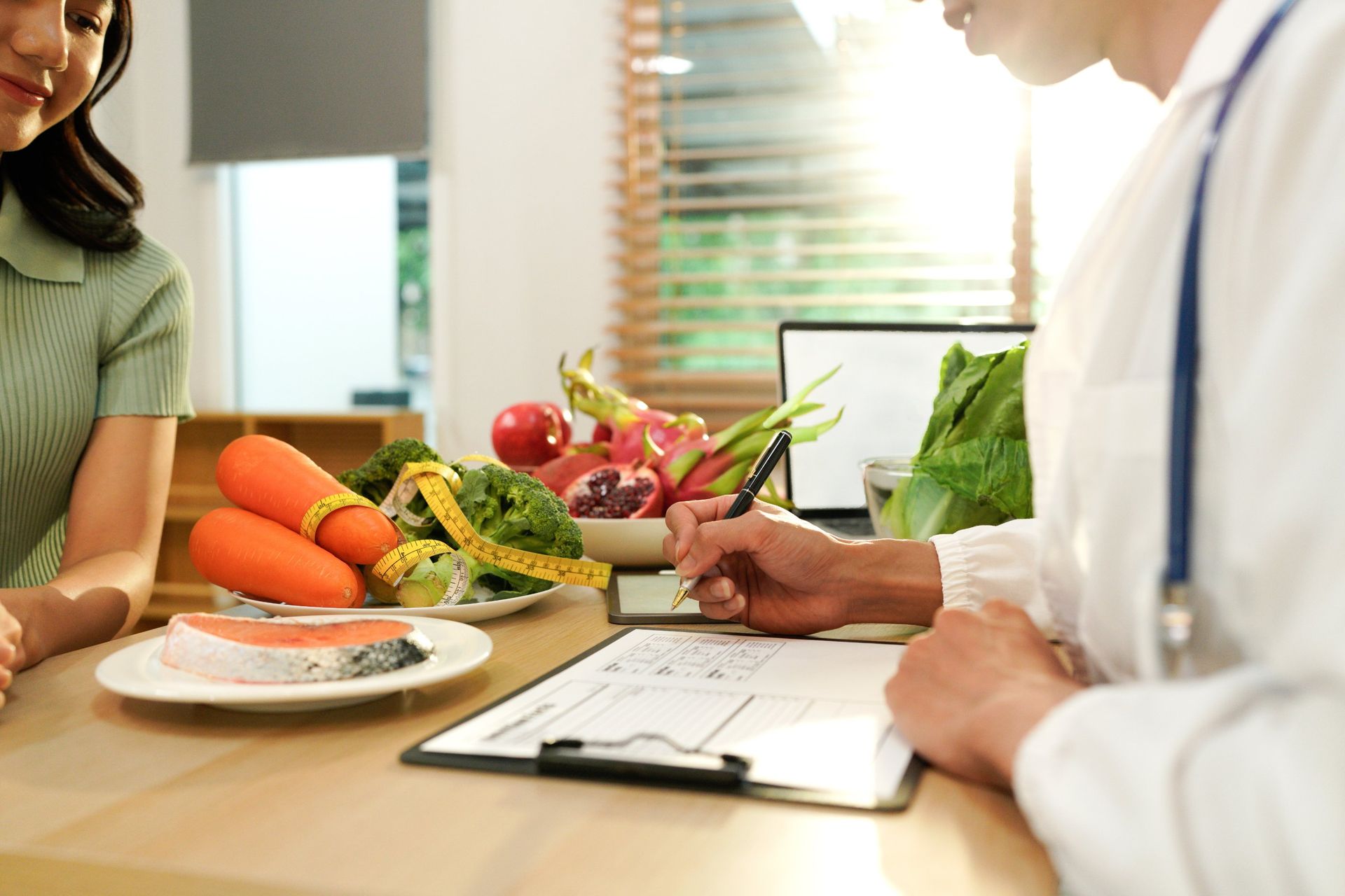 Doctor consulting with a woman at a table with vegetables and a clipboard, in a bright office