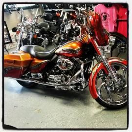 Orange-and-black custom motorcycle displayed indoors with chrome details and red front wheel