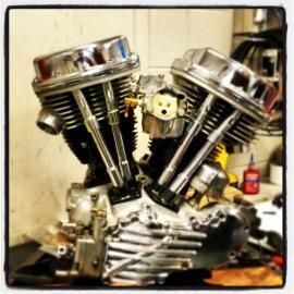 Chrome motorcycle engine sculpture with twin cylinders and polished metal parts on a workbench