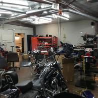 Motorcycle-filled garage with red tool cabinets and overhead fluorescent lights