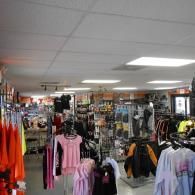 Clothing store interior with racks of colorful dresses, shirts, and accessories under bright ceiling lights