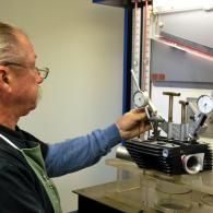 Technician inspecting a metal engine on a workbench with gauges in a workshop
