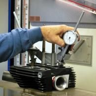 Person measuring an engine cylinder with a dial indicator in a workshop