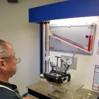 Man using a machine at a museum exhibit with a blue-and-white enclosure