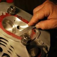 Hand tightening a wrench on a metal engine part with red gasket sealant