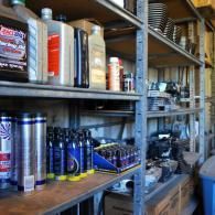 Shelves in a workshop stocked with bottles, cans, and tools