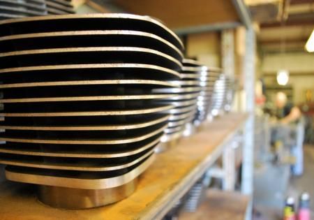 Stacked black-and-silver metal trays on a shelf in a workshop or factory.