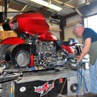 Man working on a red custom motorcycle in a garage workshop on a lift