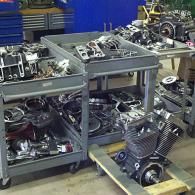 Metal shelving carts filled with automotive engines and parts in a workshop