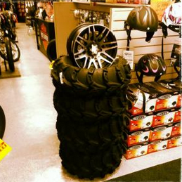 Stacked black tire rims displayed in a store aisle with boxed merchandise nearby
