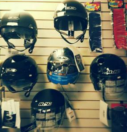 Motorcycle helmets displayed on a wall rack in a shop, mostly black with blue and red options