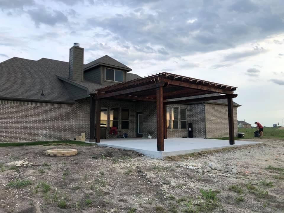Backyard patio with a covered pergola attached to a house under a cloudy sky
