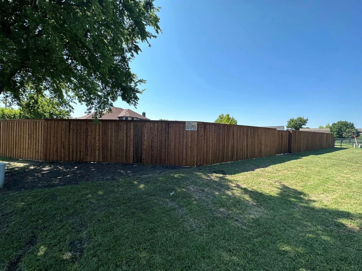 Wooden privacy fence along a grassy yard under a clear blue sky