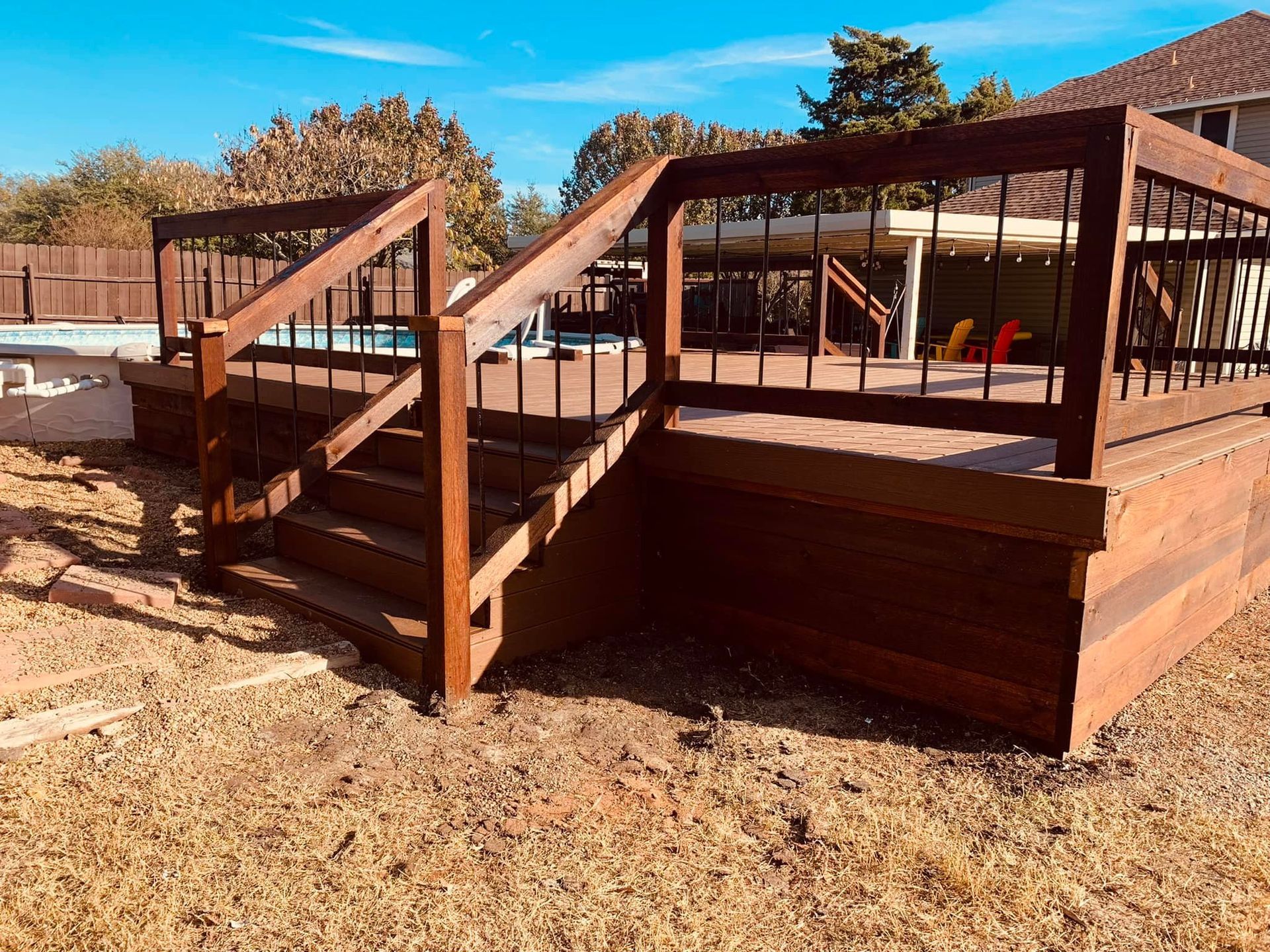 Wooden ramp and stair structure with railings on a dry, sandy lot under clear blue sky