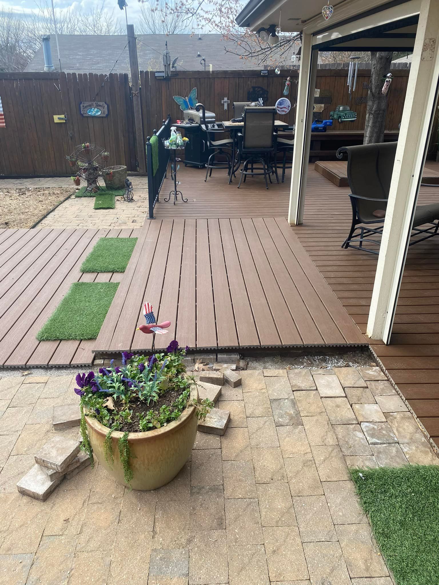Patio and backyard deck with potted flowers, stepping stones, chairs, and a covered seating area