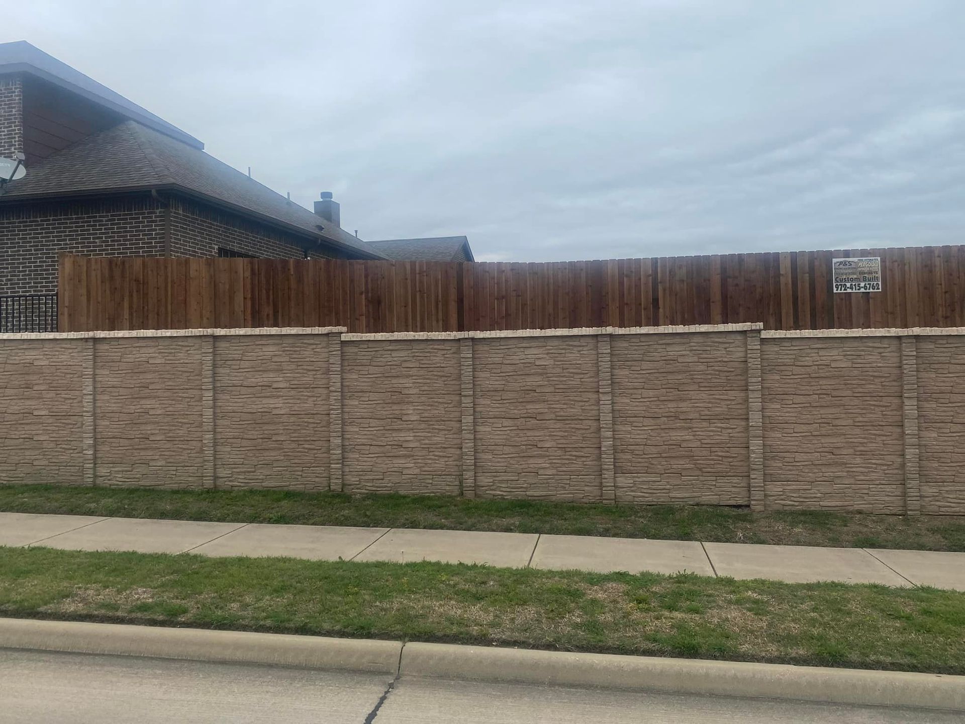 Brick wall and wooden fence along a suburban sidewalk under a cloudy sky